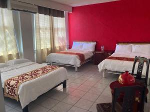 una stanza con due letti e una parete rossa di Hotel Mandarin a Tampico