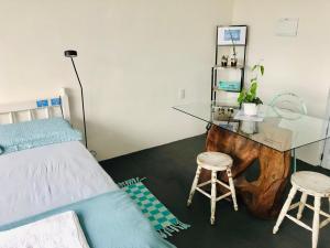 a bedroom with a bed and a desk and two stools at Pousada LUGAR - Quarto MAR familiar e tranquilo in Penha