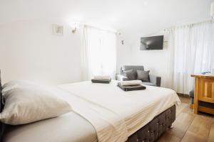 a white bedroom with a large bed and a chair at Hotel Šiška in Ljubljana +16 photos