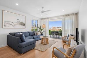 a living room with a couch and a tv at The Hamptons at Kings in Caloundra