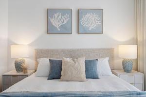 a bedroom with a white bed with two lamps at The Hamptons at Kings in Caloundra