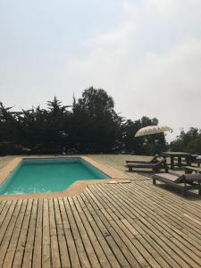 a swimming pool with a picnic table and an umbrella at Tunquén, hermosa casa, cancha de tenis y piscina exclusivas in Tunquen