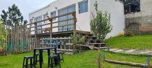 a building with a table and stools in front of it at Pousada LUGAR - Quarto MAR familiar e tranquilo in Penha
