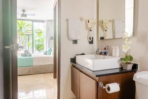 a bathroom with a sink and a mirror and a bed at Central Playa del Carmen Master Suite with rooftop pool and gym WiFi free parking near beach in Playa del Carmen +58 photos