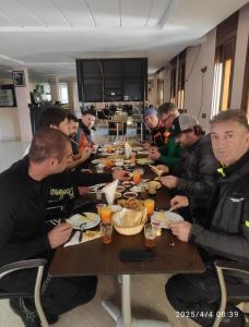a group of people sitting at a table eating food at Welcome Hôtel Dijon in Ouzoud
