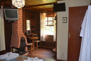 sala de estar con chimenea y TV en Pousada Cabanas do Visconde, en Visconde De Maua