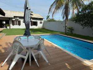 a table and chairs with an umbrella next to a pool at Caramelo hospedaria, localização privilegiada com conforto e privacidade in Sorriso