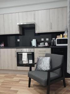 a kitchen with white cabinets and a chair and a microwave at NOVO Holiday Homes - London in Hanwell