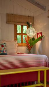 a bedroom with a yellow and red bed with a window at Surf Casitas - Mid Tide Bungalow in Santa Teresa Beach