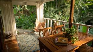 a wooden table and chairs on a porch at Surf Casitas - Mid Tide Bungalow in Santa Teresa Beach