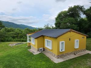 a small yellow house in the middle of a field at UMA Cabañas in Lozano