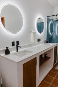 a bathroom with two sinks and two mirrors at Casa Ola Mita in Punta Mita