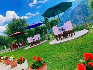 a group of chairs and umbrellas in a field at Guesthouse Silvester in Gjelaj