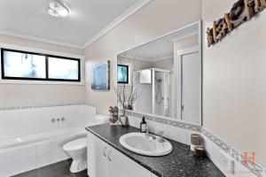 Un baño con lavabo, inodoro y espejo. en Cape Woolamai Beach House 10, en Cape Woolamai