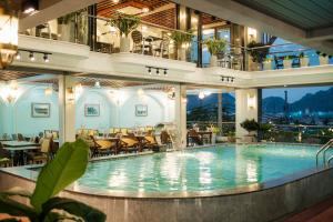 a large pool in a hotel with tables and chairs at Roza Palace Cat Ba in Cat Ba