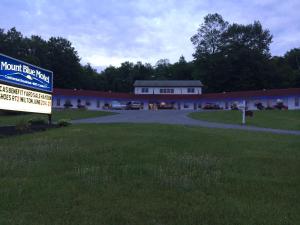 Mount Blue Motel في Farmington: لافته امام مبنى فيه موقف