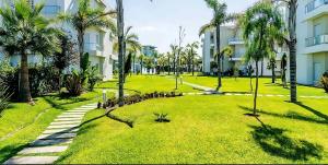 a park with palm trees in front of a building at Cosy Apartment with sea view in Sidi Rahal