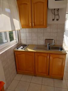 a kitchen with wooden cabinets and a sink and a window at Apartments by the sea Cove Pjestata, Peljesac - 24021 in Janjina