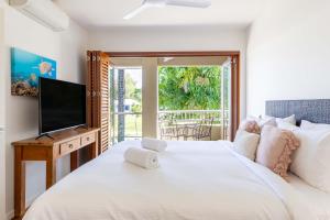 a bedroom with a large white bed and a television at Port Douglas Sea Breeze Villa 2 in Port Douglas +7 photos