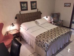 1 dormitorio con 1 cama grande y 1 silla en El Refugio, en Foz do Iguaçu