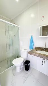 a bathroom with a toilet and a shower and a sink at Casa 3 min da praia 2 suítes churrasqueira garagem in Tramandaí +13 photos