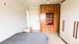 a bedroom with a bed and a wooden cabinet at Casa 3 min da praia 2 suítes churrasqueira garagem in Tramandaí