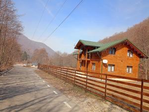 a wooden house with a fence next to a road at Cabana pe Vale in Marga +47 photos