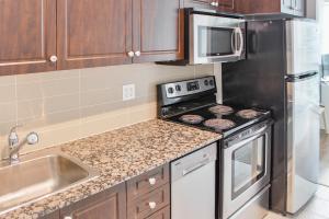 a kitchen with a stove and a stainless steel refrigerator at Panorama Luxe Suites - Prime Downtown Location in Toronto