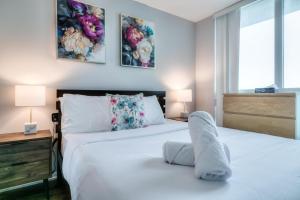 a white bedroom with two beds and two lamps at Panorama Luxe Suites - Prime Downtown Location in Toronto +11 photos