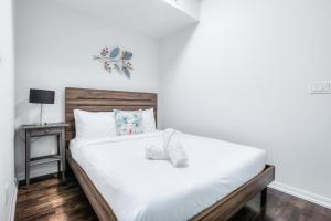 a bedroom with a white bed with a wooden headboard at Panorama Luxe Suites - Prime Downtown Location in Toronto +4 photos