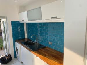 cocina con fregadero y pared de azulejos azules en NEW!! Whole House with Mod Cons, Close to transport links, en South Norwood