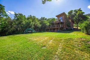 a large house on a grassy field in front at Glenwood Springs Mountain Getaway with Hot Tub and Riverfront in Glenwood Springs