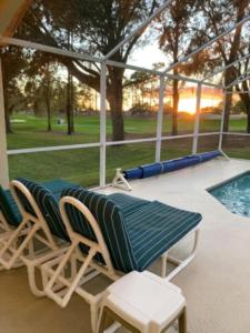 zwei Stühle und eine Bank auf einer Terrasse mit einem Pool in der Unterkunft Villa Sixteen Southern Dunes in Haines City + 24 Fotos