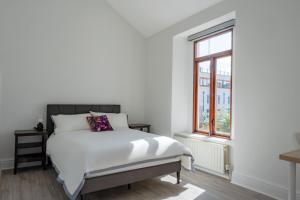 a white bedroom with a bed and a window at Eblana House in Dublin