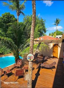 a wooden deck with chairs and a swimming pool at Bangalô Suíte Sol do Gostoso in São Miguel do Gostoso