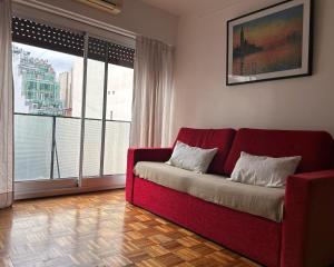 a red couch in a living room with a large window at Sarmiento Home in Buenos Aires
