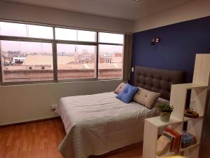 Un dormitorio con una cama con paredes y ventanas azules. en Misti Suite, en Arequipa