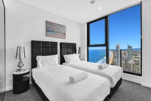 two beds in a room with a large window at Serain Residences on 88 Esplanade Surfers Paradise in Gold Coast +72 photos