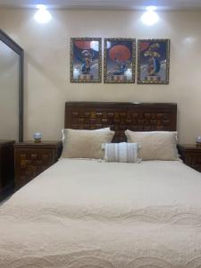 a bedroom with a large white bed with three pictures on the wall at Residence Adja Binta Kane Sour in Dakar