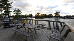 a wooden deck with a picnic table and two chairs at Riverfront Cottages in Wasaga Beach