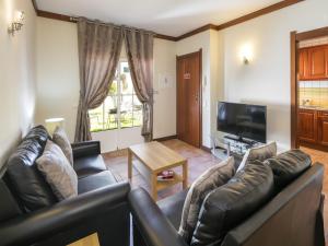 a living room with a leather couch and a television at Holiday home near Praia de Benagil beach in Benagil