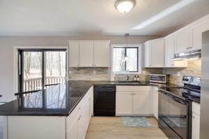 a kitchen with white cabinets and a black counter top at Blue Wolf Retreat Pool Table Cozy BBQ in Albrightsville