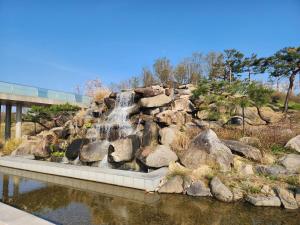 a waterfall in a garden with rocks and water at Plantree filled with the charm of the East and the atmosphere of the West in Seoul