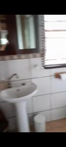 a bathroom with a white sink and a window at Rhulani Treetop Cottage in Marloth Park +9 photos