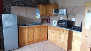 a kitchen with wooden cabinets and a stainless steel refrigerator at Rhulani Treetop Cottage in Marloth Park