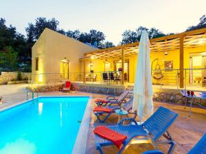 a pool with chairs and an umbrella next to a house at Villa in Armenoi near Rethymno Beaches in Fotinós