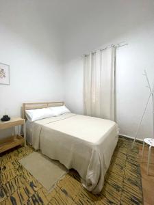 a white bedroom with a bed and a table at Akaiah in Santo Domingo