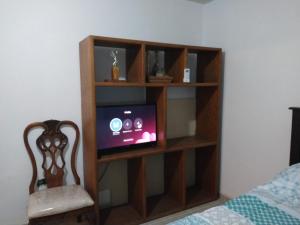 a book shelf with a tv and a chair in a room at Agradable habitación A in Mexicali