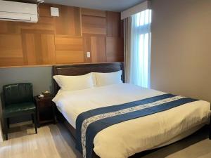 een slaapkamer met een bed met een stoel en een raam bij 大同ガーデンホテル京都 in Kyoto