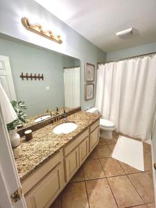a bathroom with a sink and a toilet and a mirror at 2700sq ft Condo in Gulf Shores in Gulf Shores